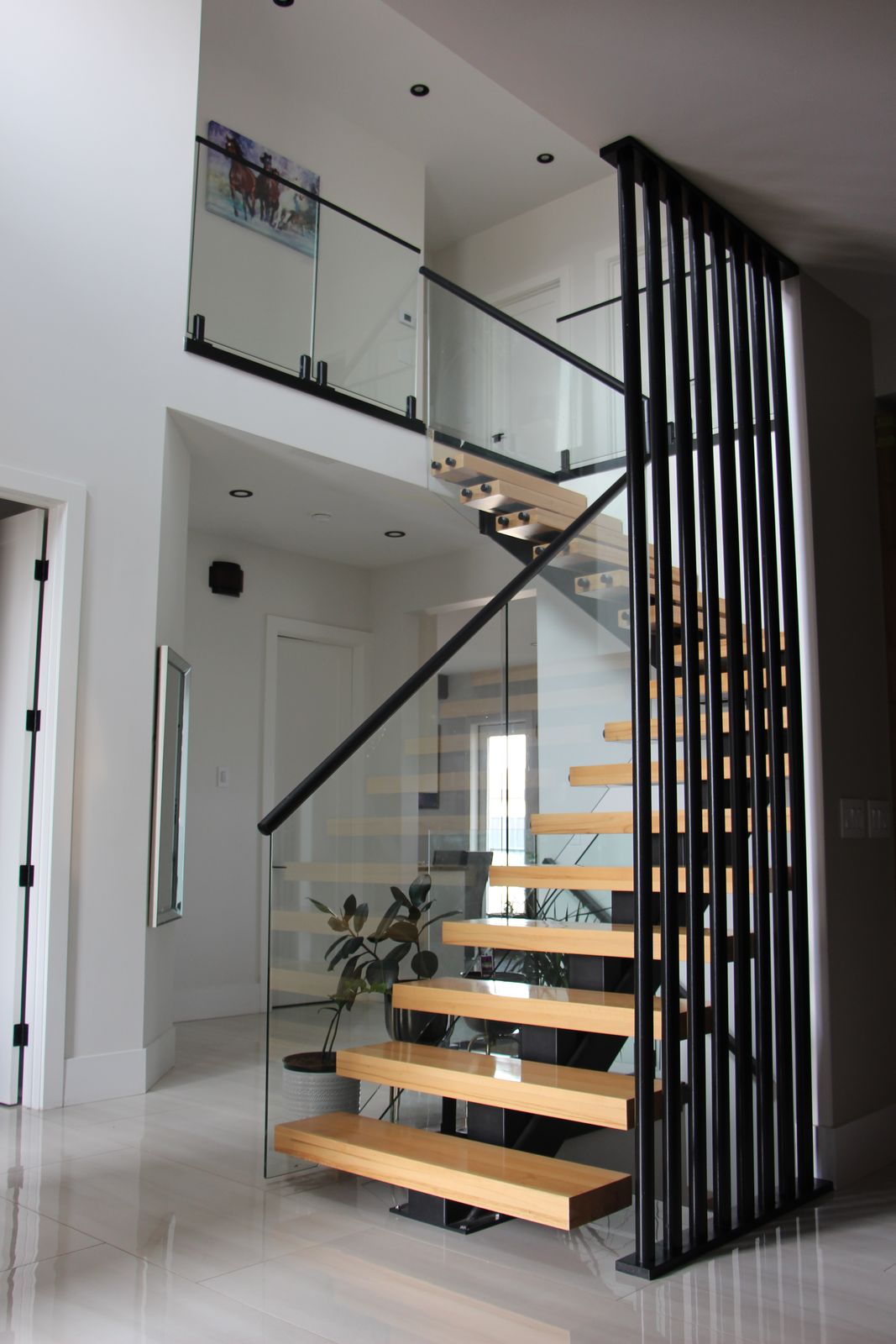 Floating oak staircase with glass railing in a bright open entry